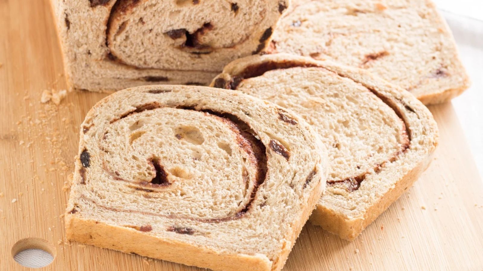 Slices of cinnamon raisin bread on a wooden board.