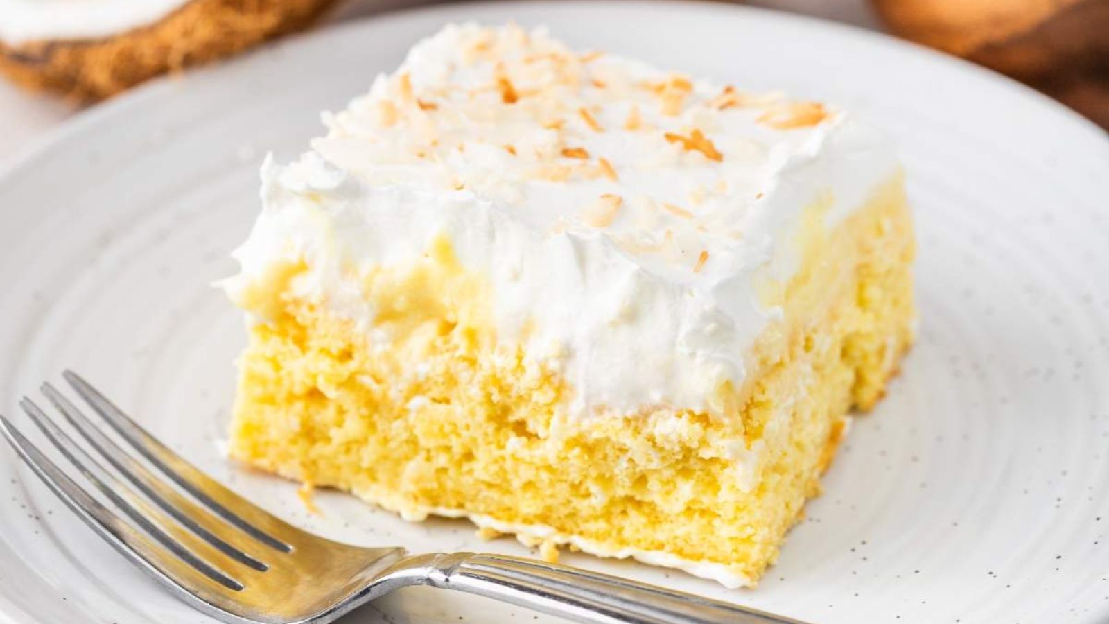 A slice of poke cake with coconut.