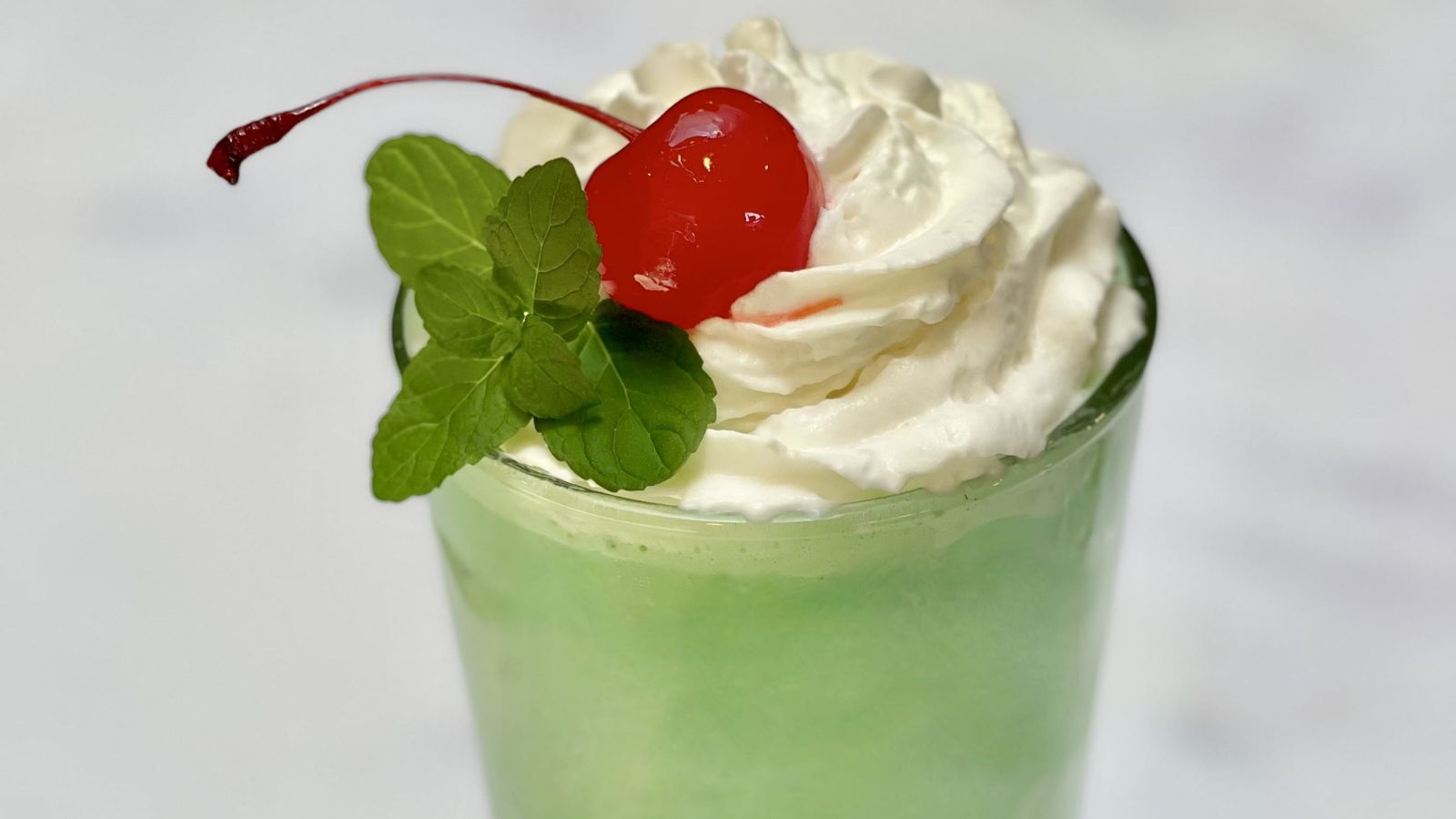 Shamrock shake in a glass with whipped cream and cherry.