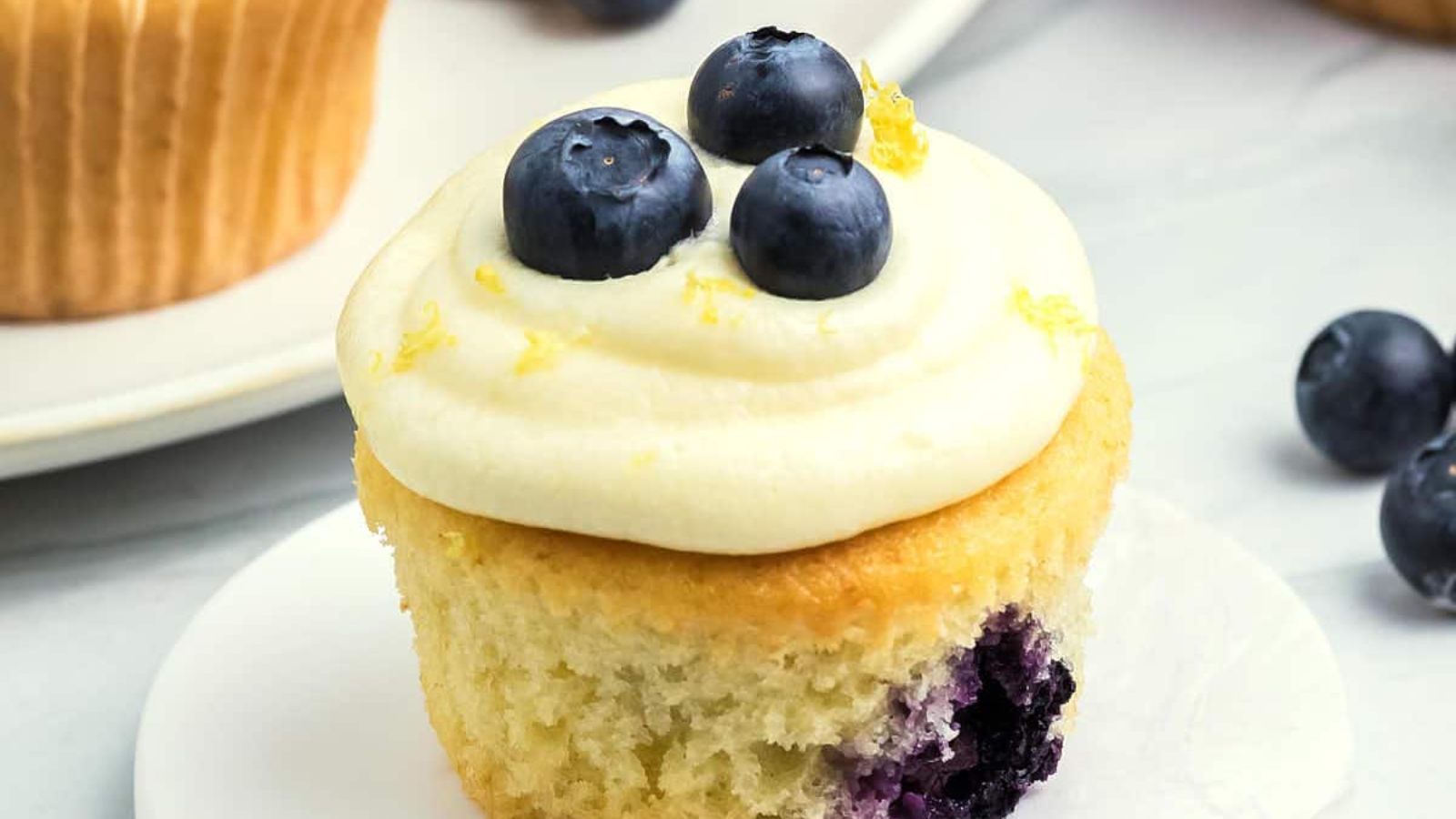 Lemon cupcake with blueberries on top.