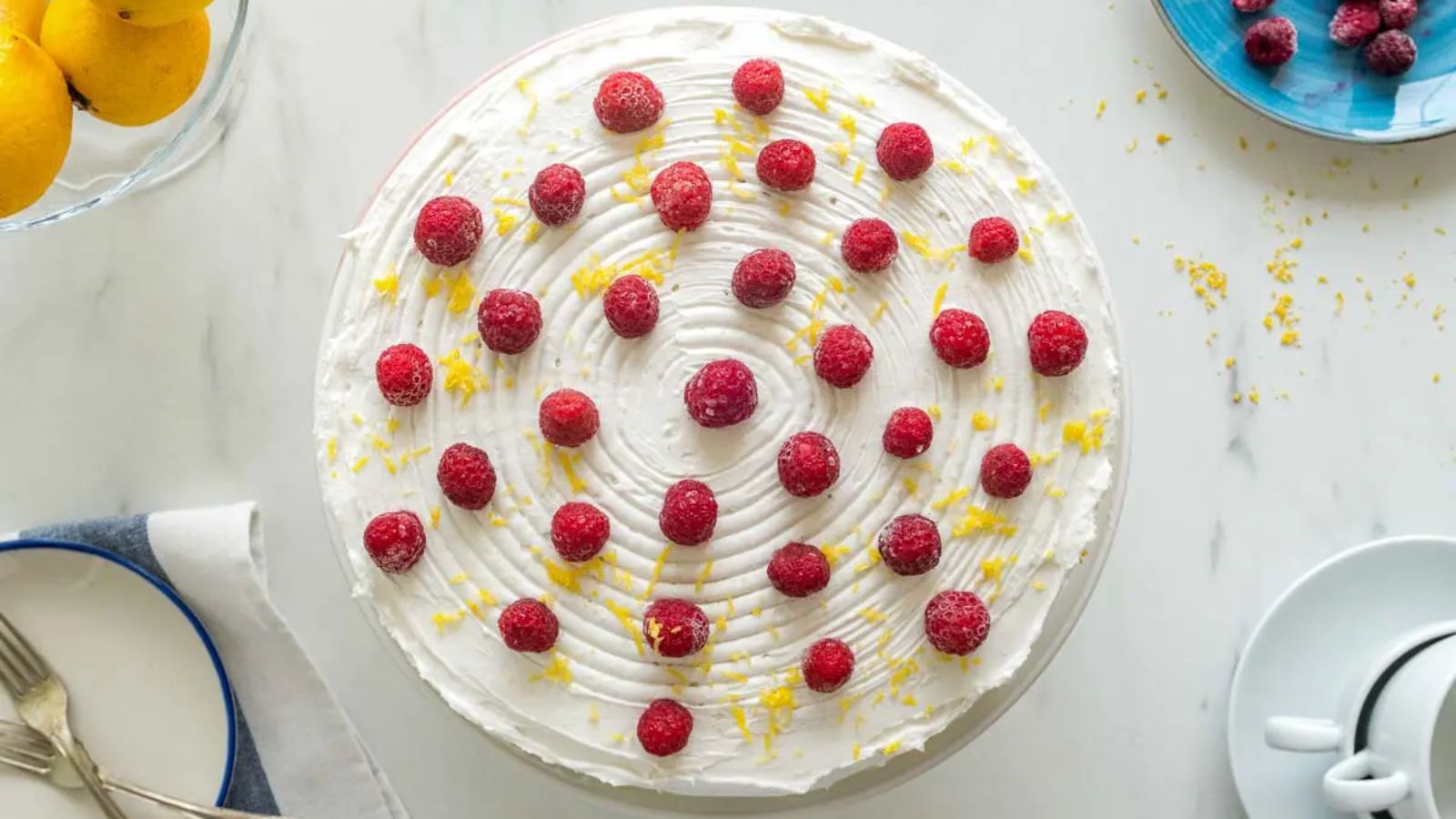 A whole lemon cake with raspberries on top.