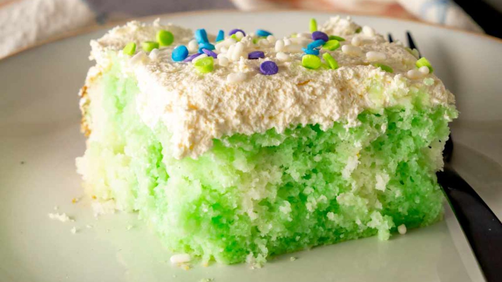 A slice of lime poke cake on a plate.