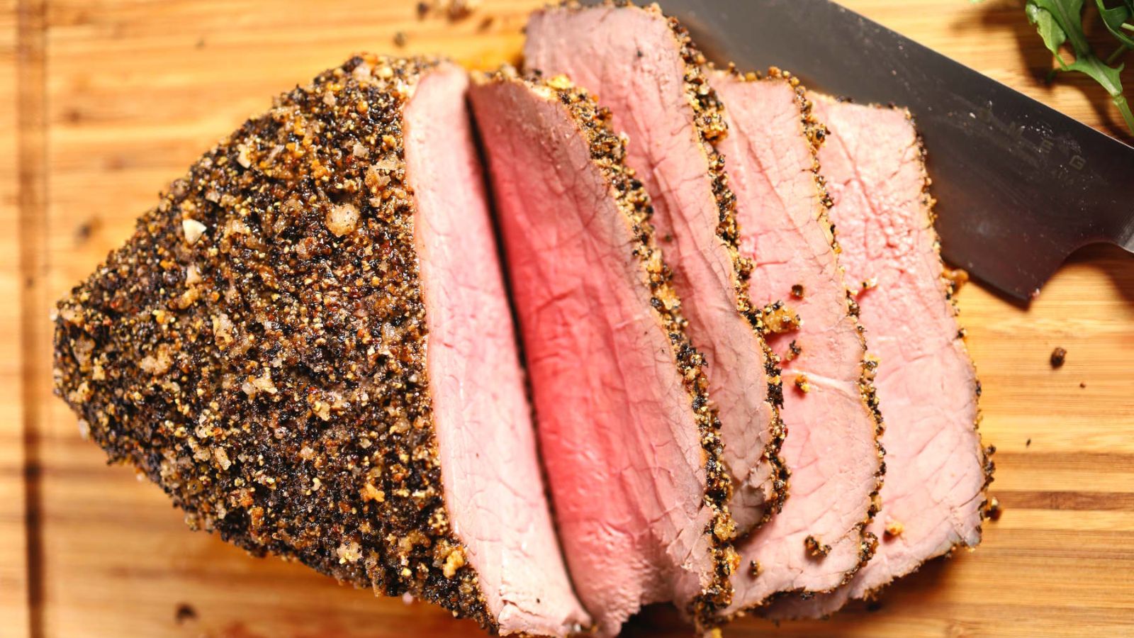 Sliced roast beef on a wooden board.