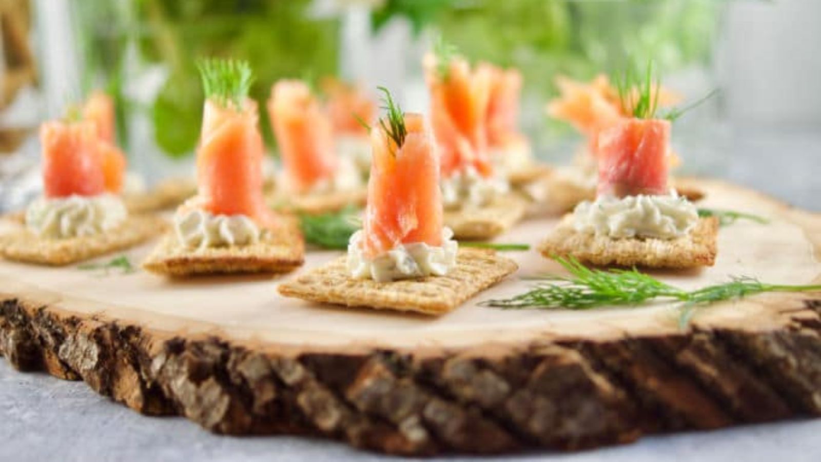 Salmon and dill canapes on a wooden board.