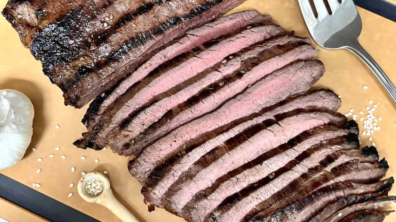 Sliced flank steak on a wooden board.