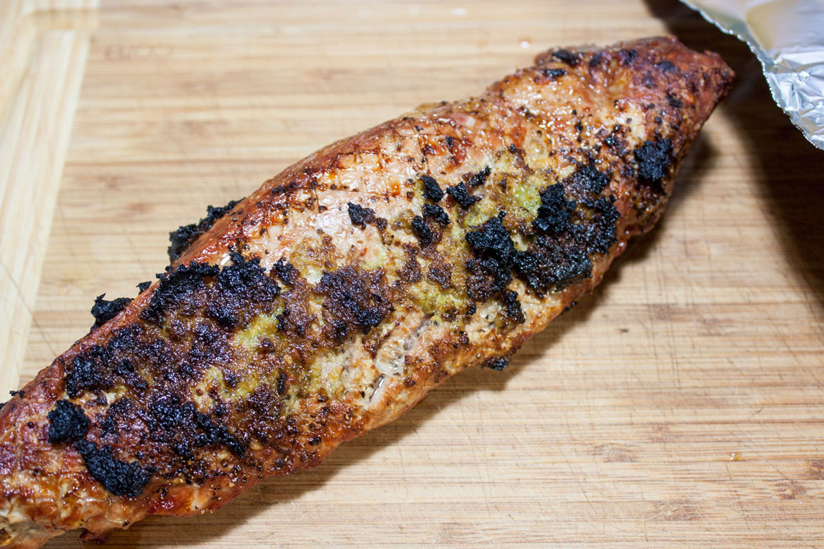 Meat resting on a wooden board.