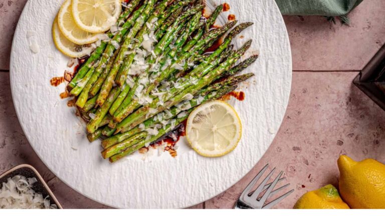 Asparagus on a white plate with lemons.