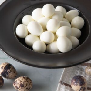 Black bowl filled with hard boiled quail eggs.