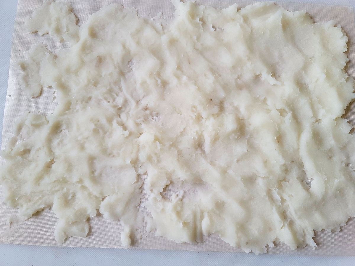 Mashed potatoes spread on a dehydrator tray.