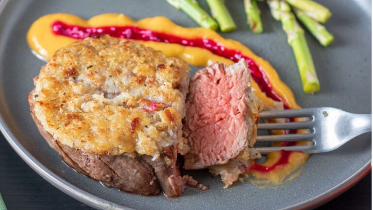 Fork holding a slice of beef tenderloin.