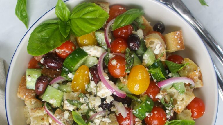 Colorful panzanella salad in a white bowl.