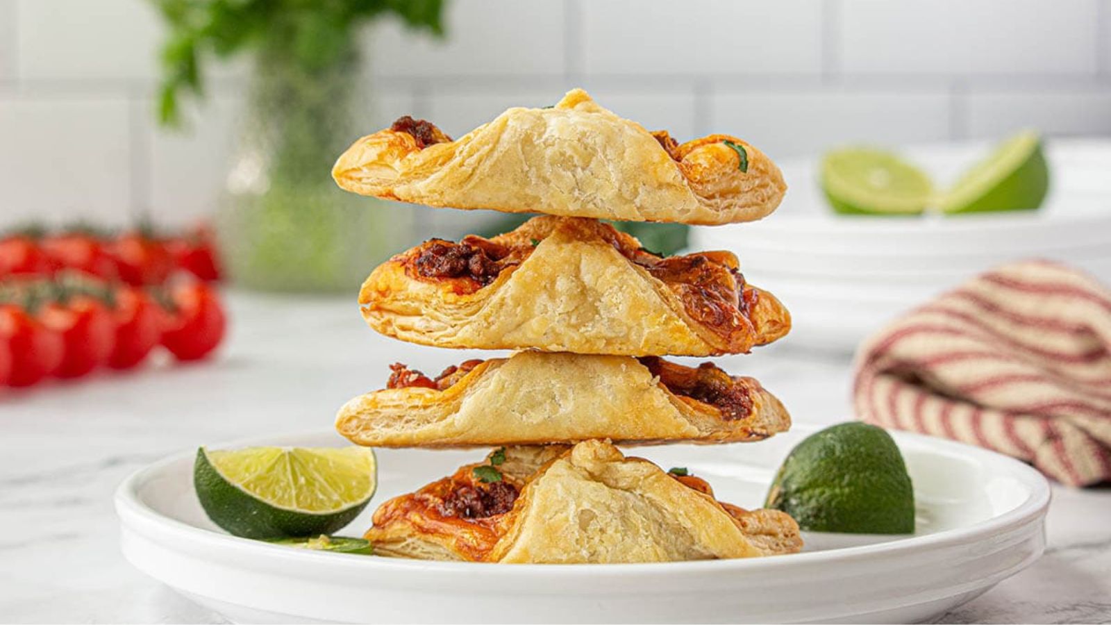 Stack of puff pastry tacos on a white plate.