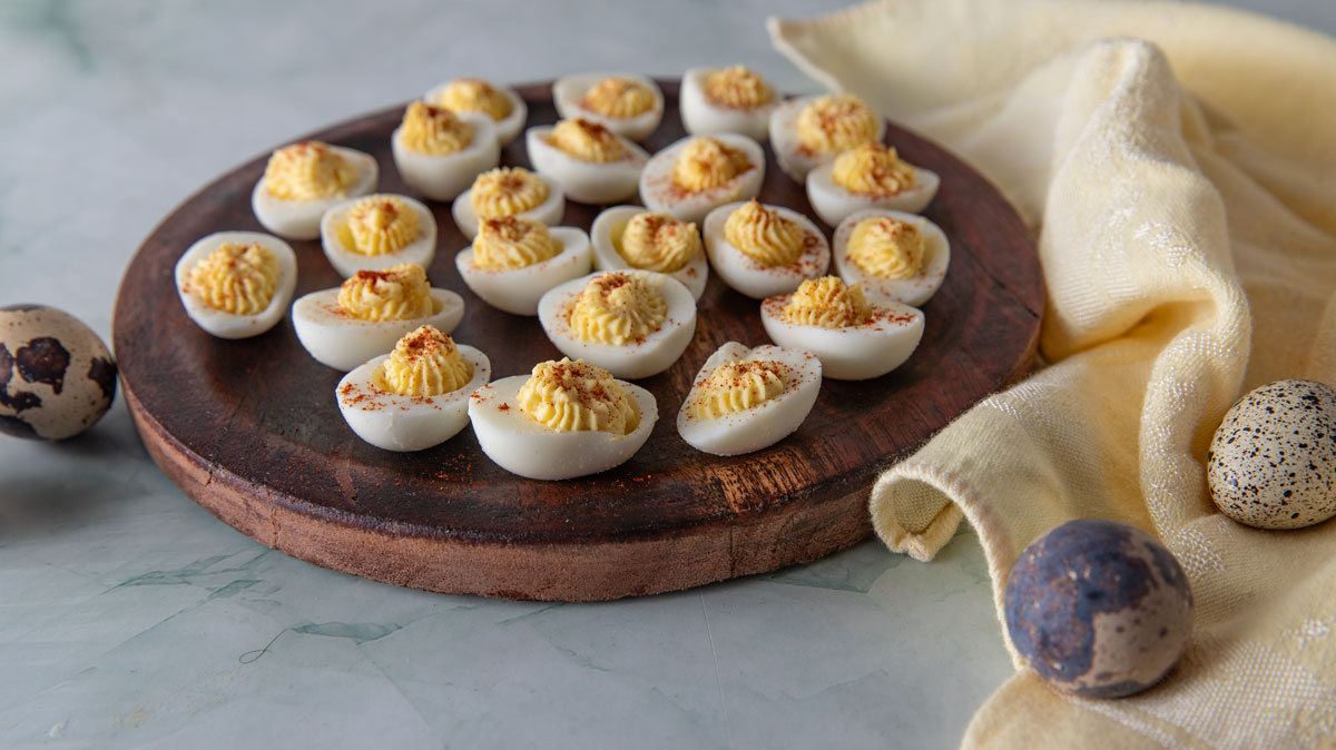 Filled deviled quail eggs on a brown plate.