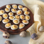 Deviled quail eggs on a wooden plate.
