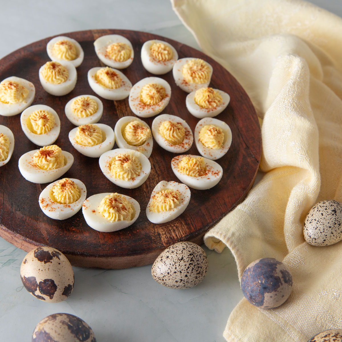 Deviled quail eggs on a wooden plate.