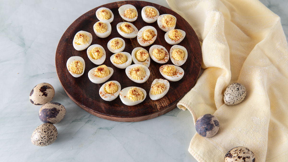 Deviled quail eggs on a wooden plate.