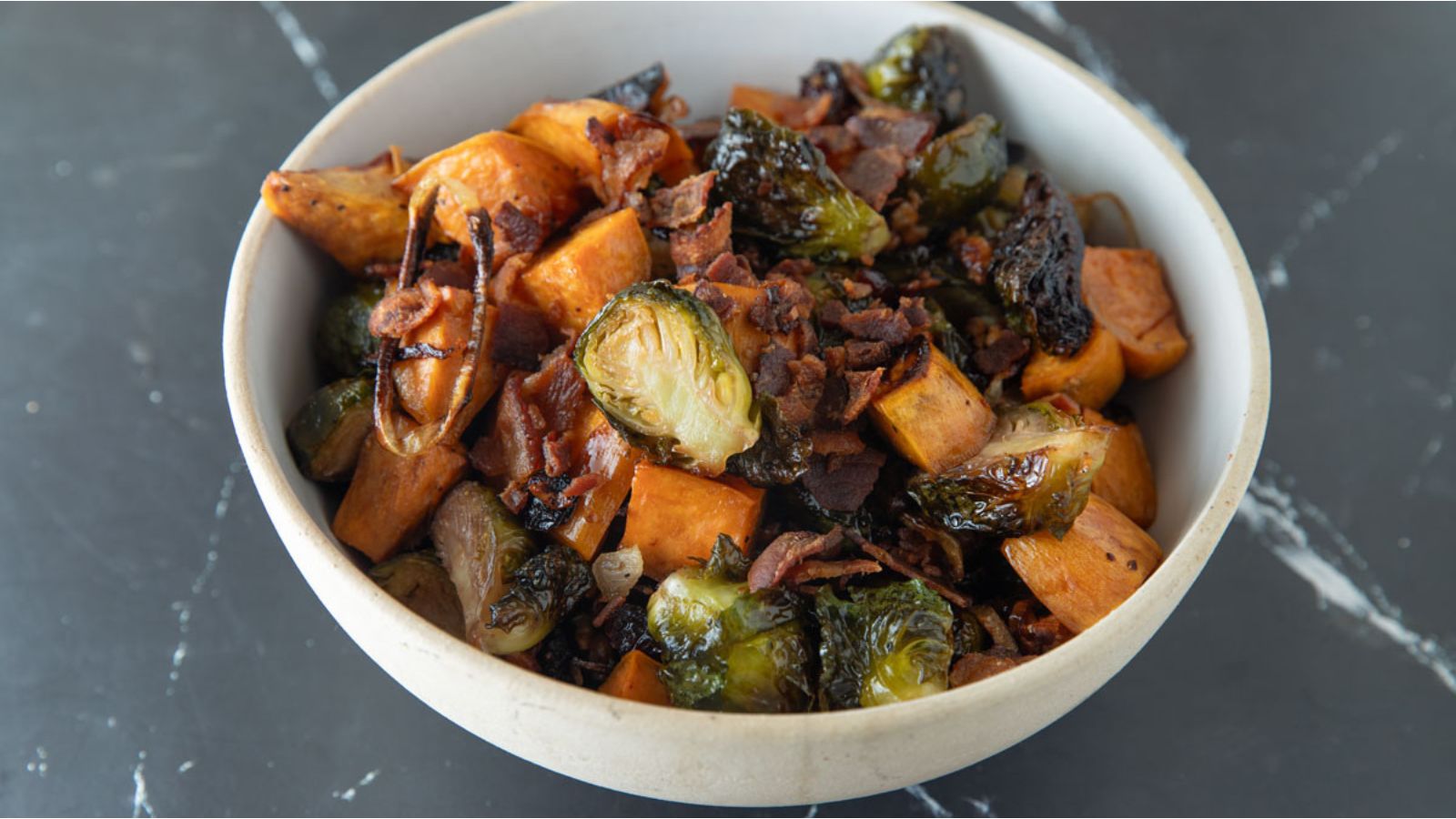 Beige bowl with crispy brussels sprouts and sweet potatoes.