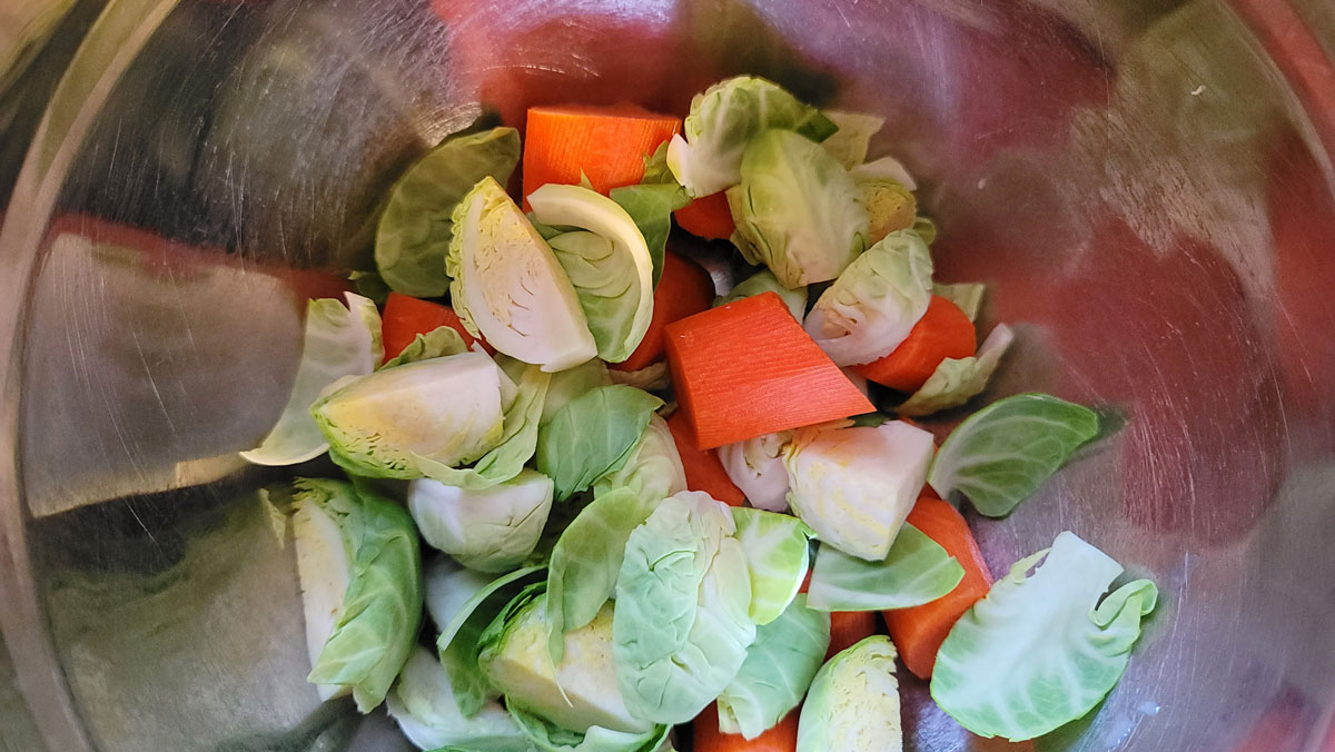 Cut brussels sprouts and carrots in a large bowl.
