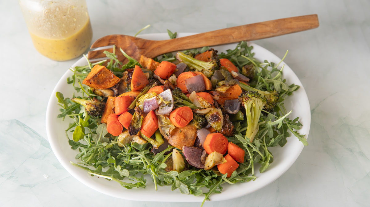 Oval platter filled with arugula and roasted veggies.