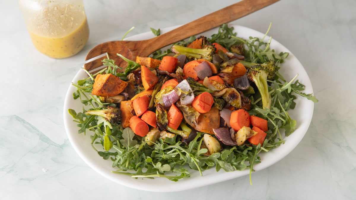 Platter of roasted vegetables on a bed of arugula.