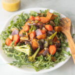 Platter filled with roasted vegetable salad on a bed of arugula.