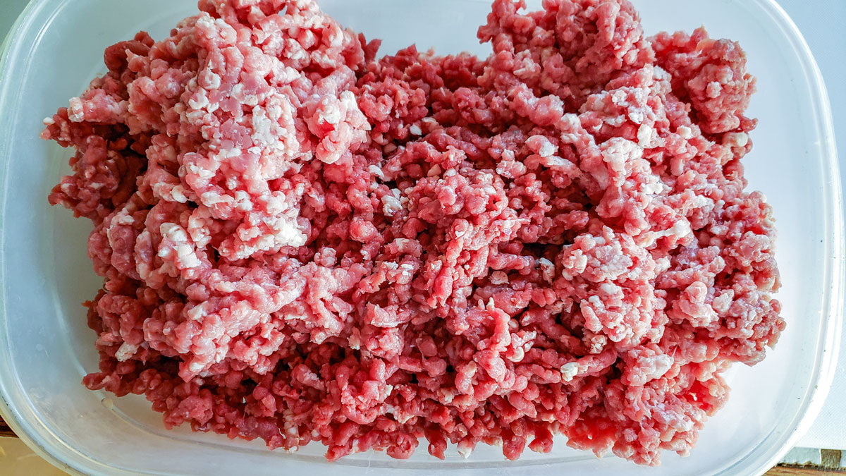 Meat mixed up in a large container.