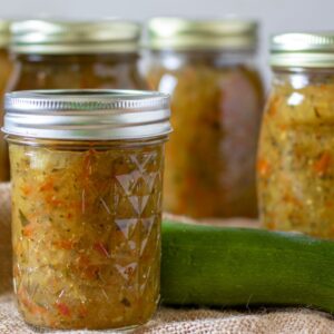 Jars of zucchini relish on a piece of burlap.