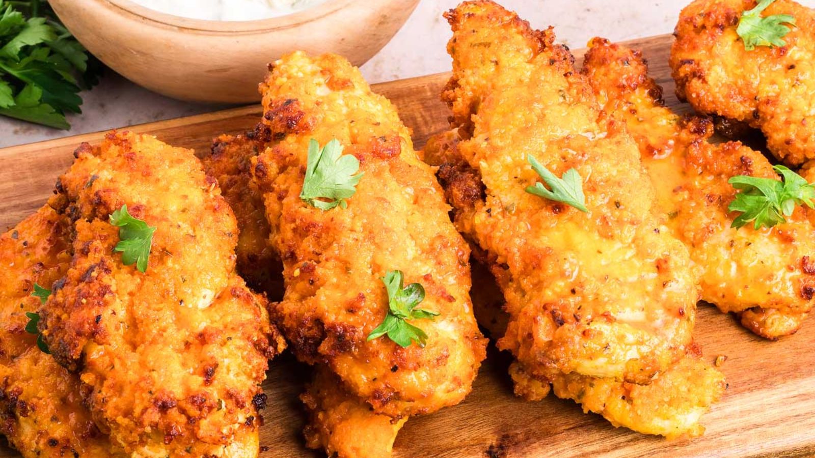 Chicken tenders on a wooden board.