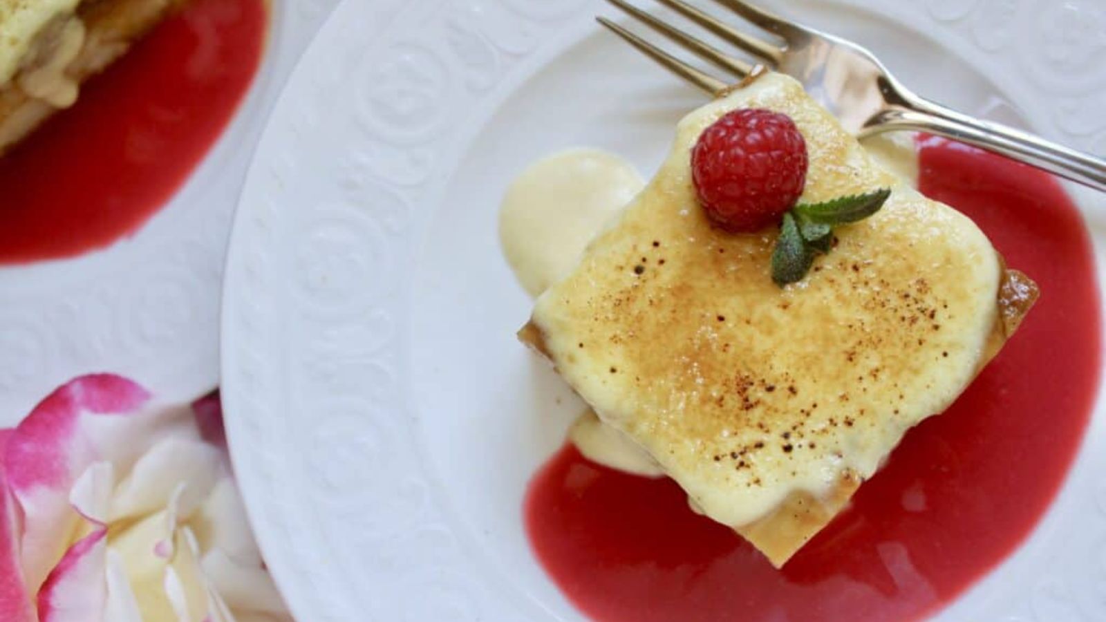 Custard pudding with raspberry topping on a plate.