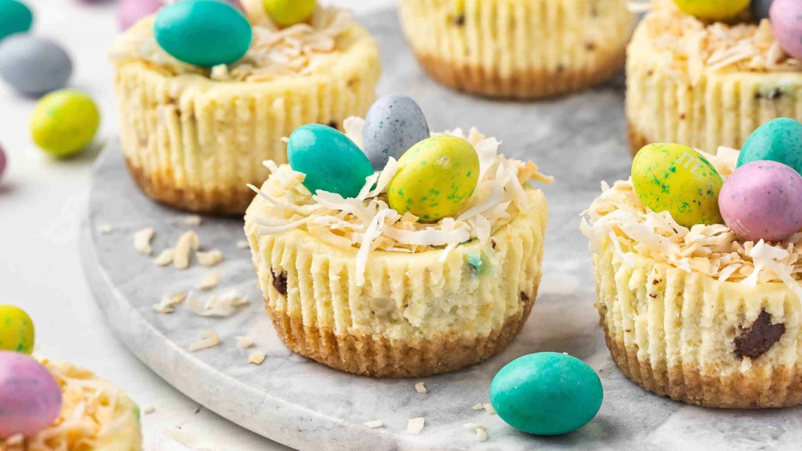 Mini Cheesecakes cups on a plate with chocolate eggs.