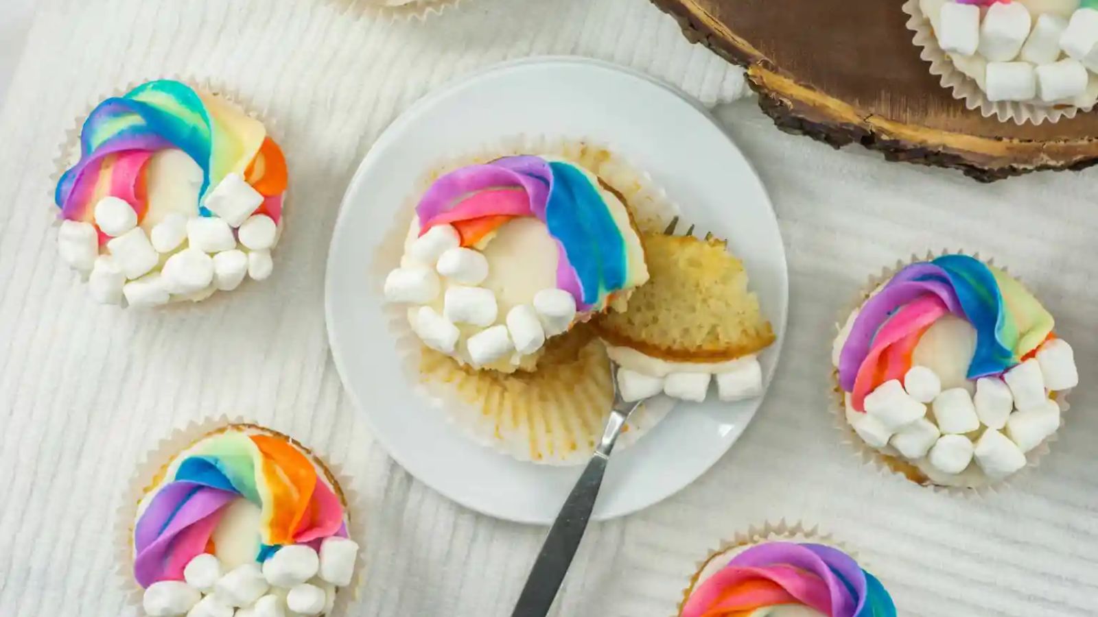 Cupcakes with rainbow frosting on a plate.