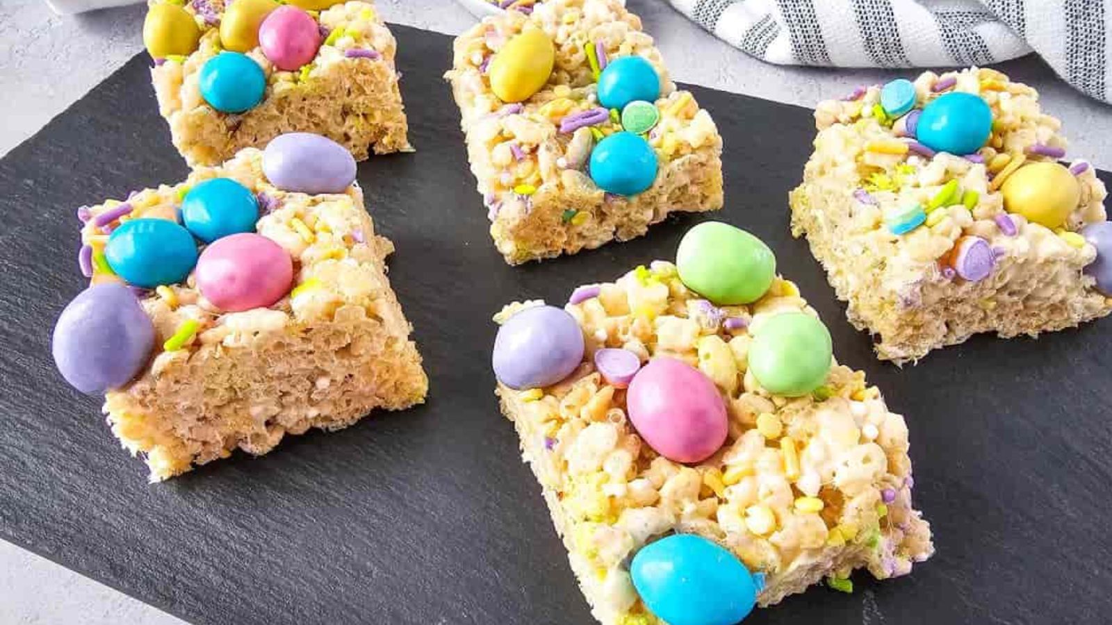 M&M rice krispie bites on a wooden plate.