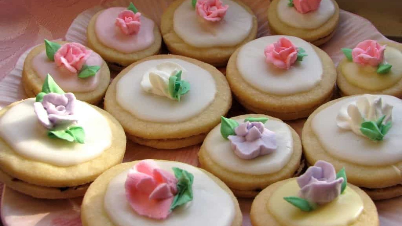 12 pastle cookies with flowers design on top.