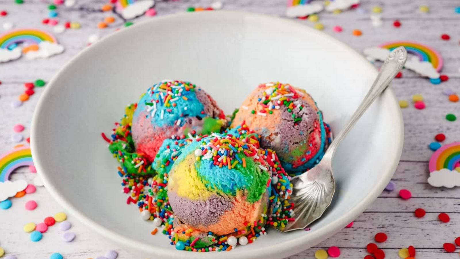 Rainbow ice cream with sprinkles in a bowl.