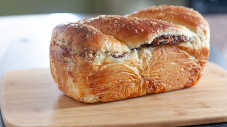 Loaf of cozonac on a wooden cutting board.