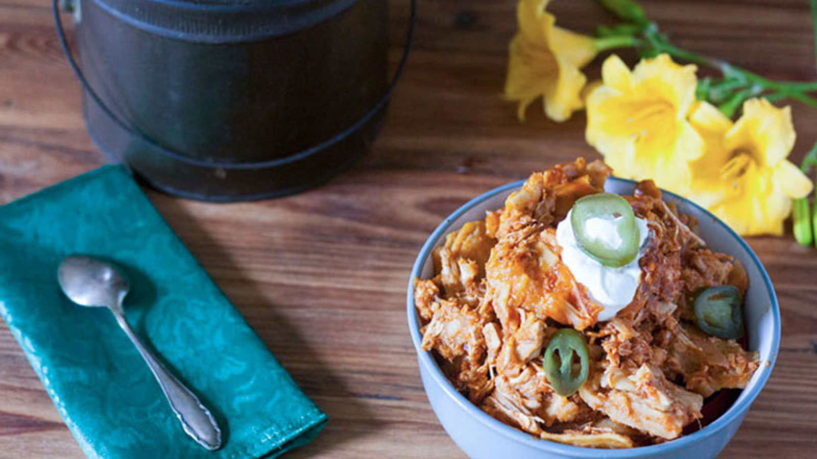 Gray bowl filled with enchilada casserole and topped with sour cream.