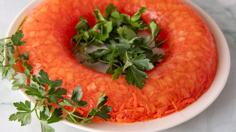 Orange jello mold garnished with parsley garnish.