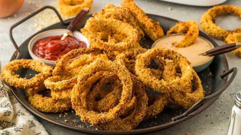 Air fryer onion rings on a plate with catsup on side.