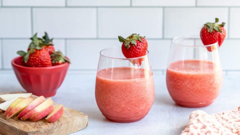 2 apple strawberry smoothie on a glass with strawberry on side.