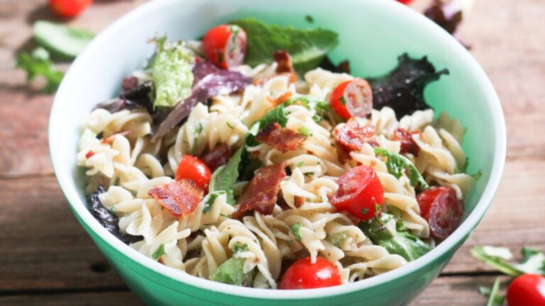 Pasta salad with colorful tomatoes and leaf lettuce and cripsy bacon.