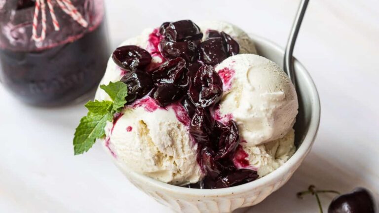 Cherry compote with cherry on top on a bowl.