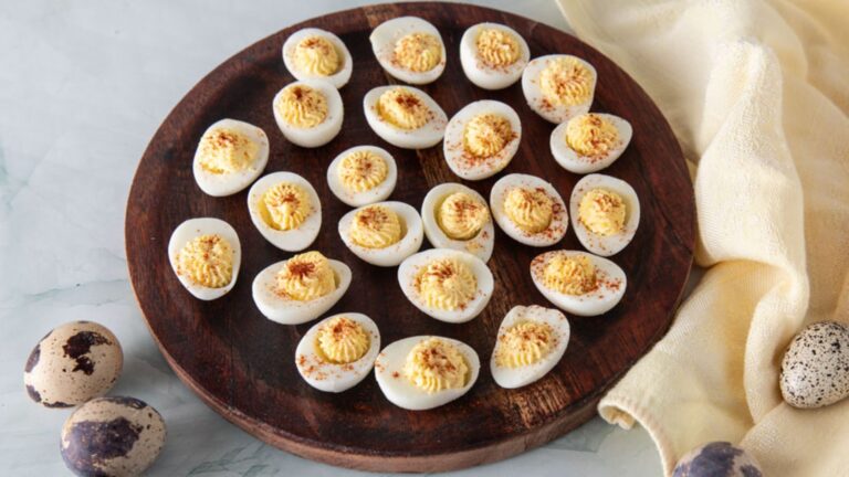 Deviled quail eggs on a wooden plate.