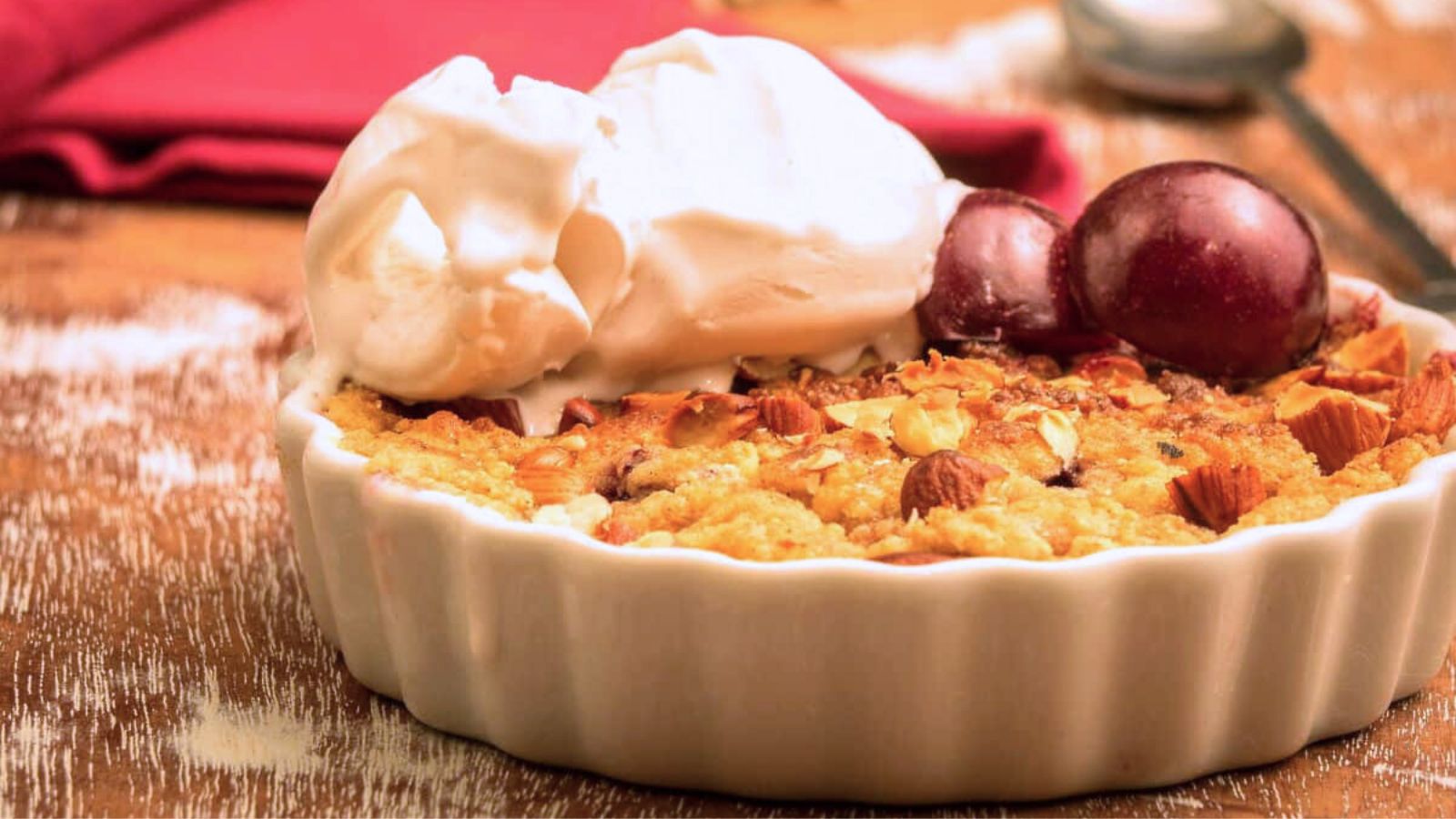 Plum Crumble topped with halved pulms and scoops of ice cream.