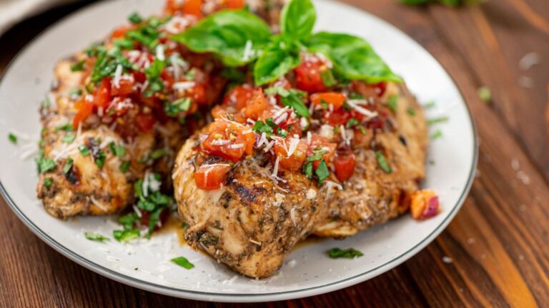 Bruschetta chicken with herb on top on a plate.