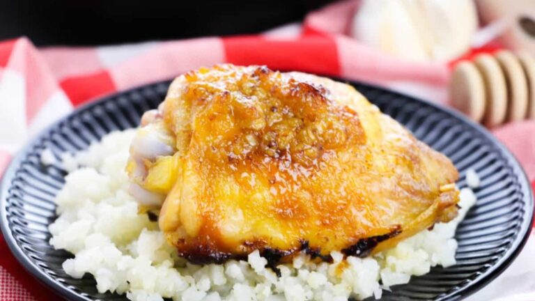 Honey mustard chicken thigh with rice on a plate.