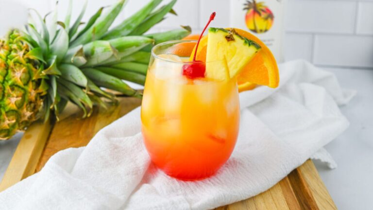 Malibu sunset cocktails with fruits on top on a glass.