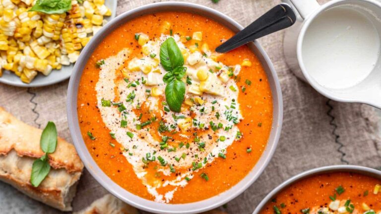 Roasted tomato and corn soup on a bowl with herbs.