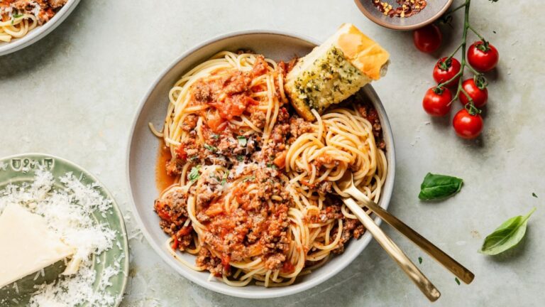 Spaghetti with meat sauce and bread on a plate.