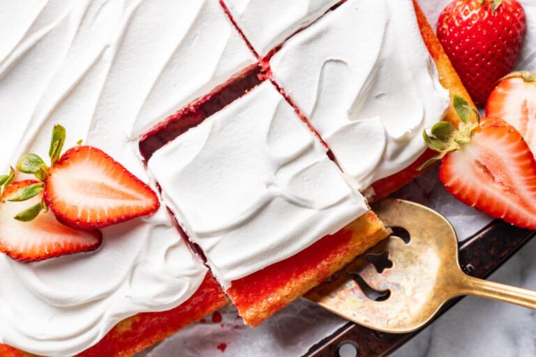 Strawberry Jello Poke cake with a cake server removing a piece from the cut cake.