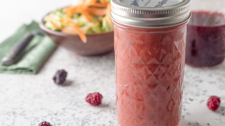 Jar of blackberry vinegar and vinaigrette on white board.